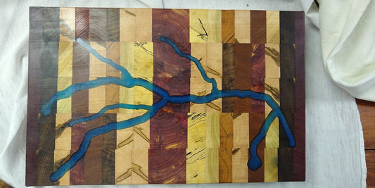 Large end grain butcher block cutting board made from 11 different types of wood with an acrylic river